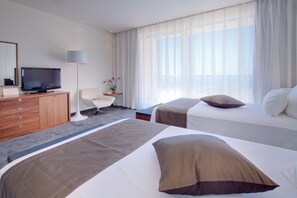 Habitación de hotel con dos camas, televisión, escritorio y una silla.