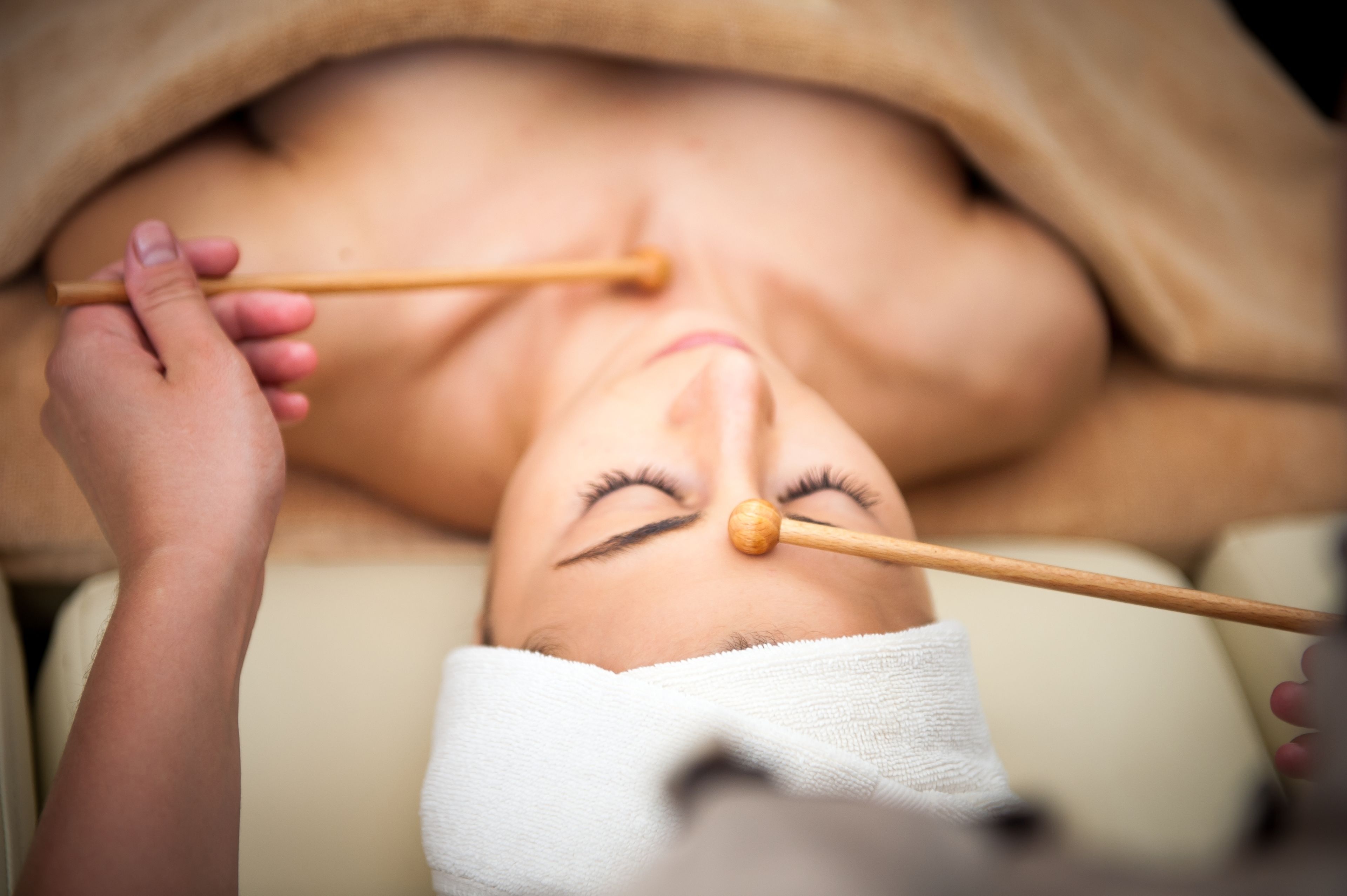 A person lying down with a wooden stick held by another person.