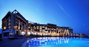 A multi-story hotel with a swimming pool, outdoor seating, and a covered walkway. - Lighthouse Golf and Spa Hotel (Balchik)