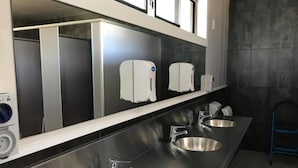 A modern bathroom with three stainless steel sinks, a mirror, and hand dryers. - Glentanner Park Centre (Glentanner)