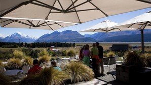 An outdoor seating area with tables and chairs under large umbrellas, overlooking a mountainous landscape with a clear sky. - Glentanner Park Centre (Glentanner)