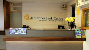 A reception desk at Glentanner Park Centre with a logo, a vase of yellow flowers, and informational brochures. - Glentanner Park Centre (Glentanner)