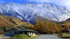 A mountain lodge with a simple, functional design, featuring a parking area and a small building with a covered porch. - Glentanner Park Centre (Glentanner)