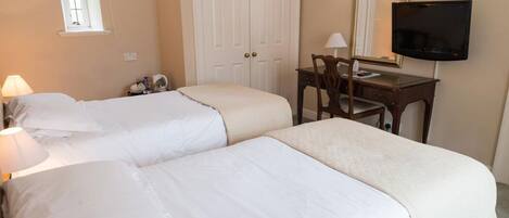 A hotel room with two beds, a desk with a chair, a television, and a wardrobe.
