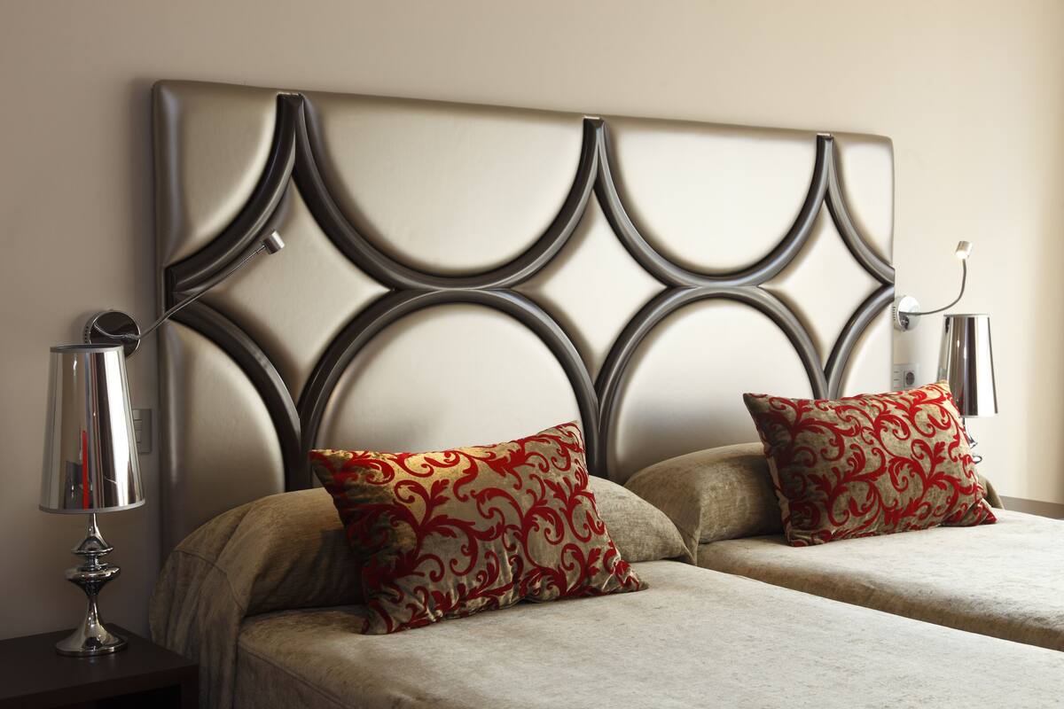 A double bed with a decorative headboard and two matching pillows.