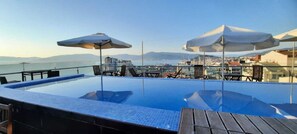 An infinity pool with a clear view of the city and mountains in the background. - Hotel Silken Axis Vigo (Vigo)