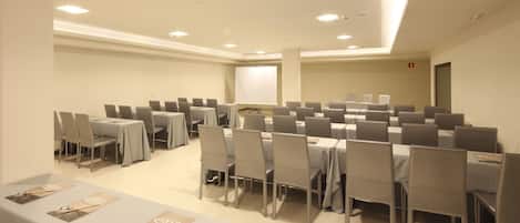 Un salón de conferencias con varias mesas y sillas dispuestas en filas.