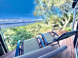 A deck with two lounge chairs overlooking a scenic view of a lake and hills. - Acacia Cliffs Lodge (Taupo)