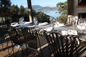 A dining table set for six with black chairs, overlooking a scenic view of a lake and mountains. - Acacia Cliffs Lodge (Taupo)