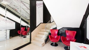 Un interior moderno con una escalera, sillas rojas y un mostrador de recepción blanco.