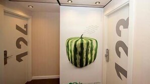 Un pasillo con una obra de arte de sandía colgada en la pared y flechas direccionales en las puertas.