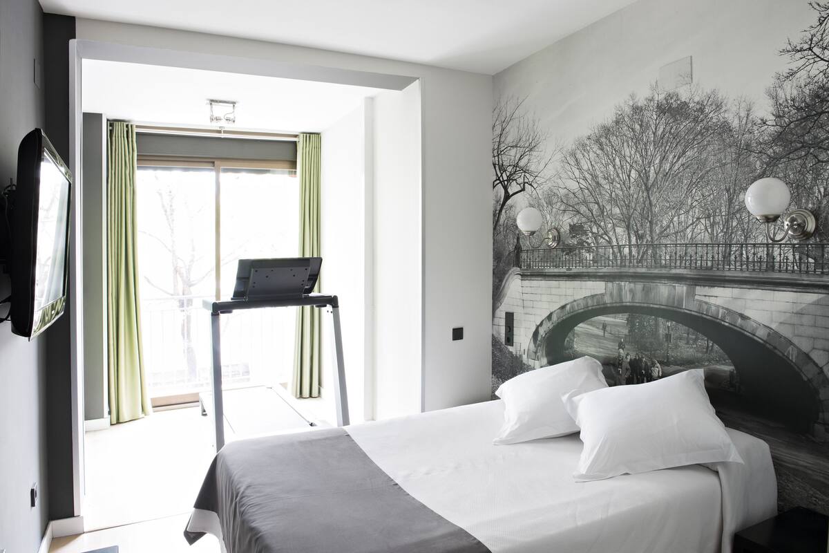 Une chambre d’hôtel avec un lit, un bureau et une fresque représentant un pont.