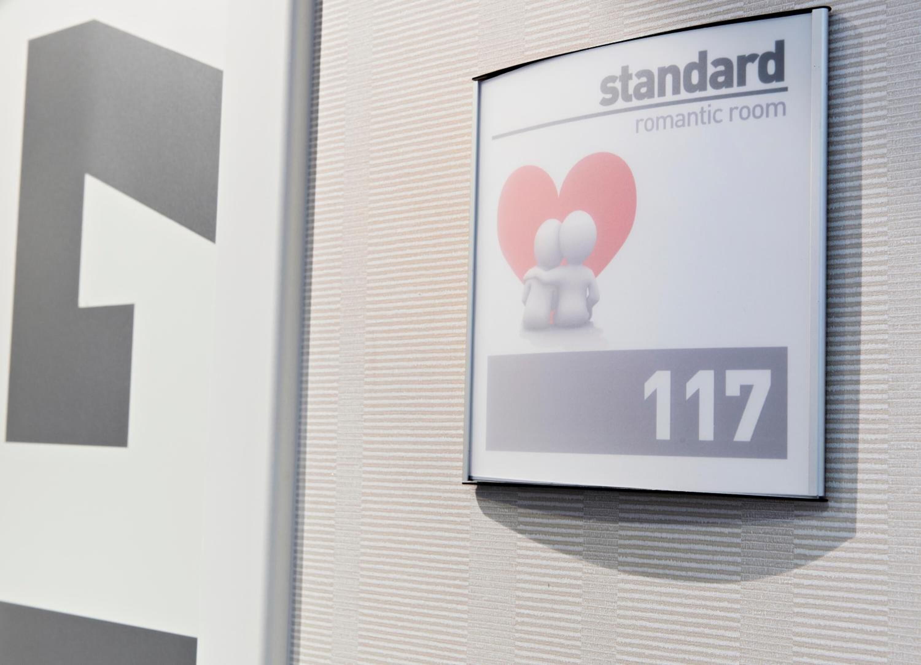 Een bordje voor een 'standaard romantische kamer' met een hartsymbool en het nummer 117.