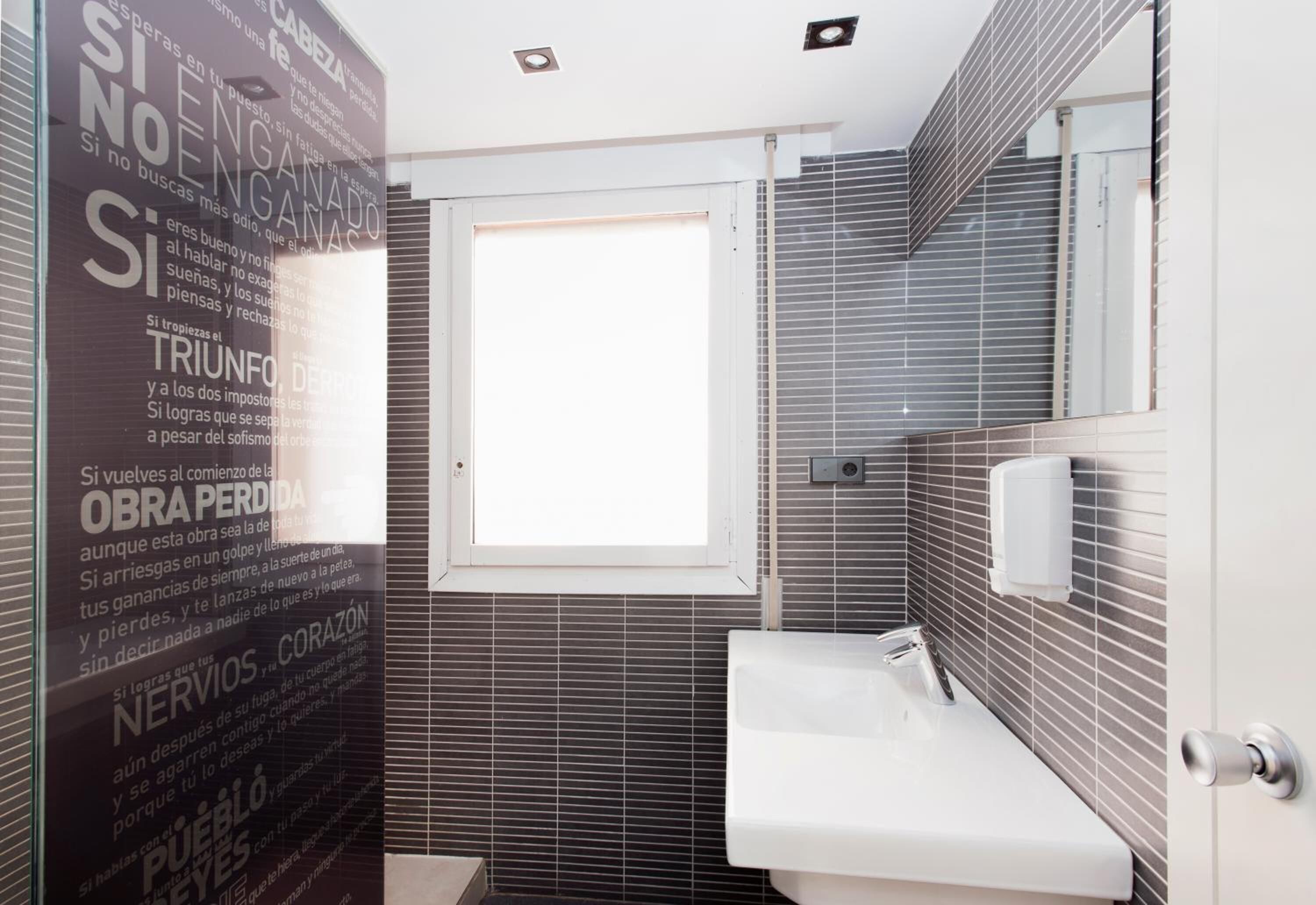 A modern bathroom with a large mirror, a sink, and a window.