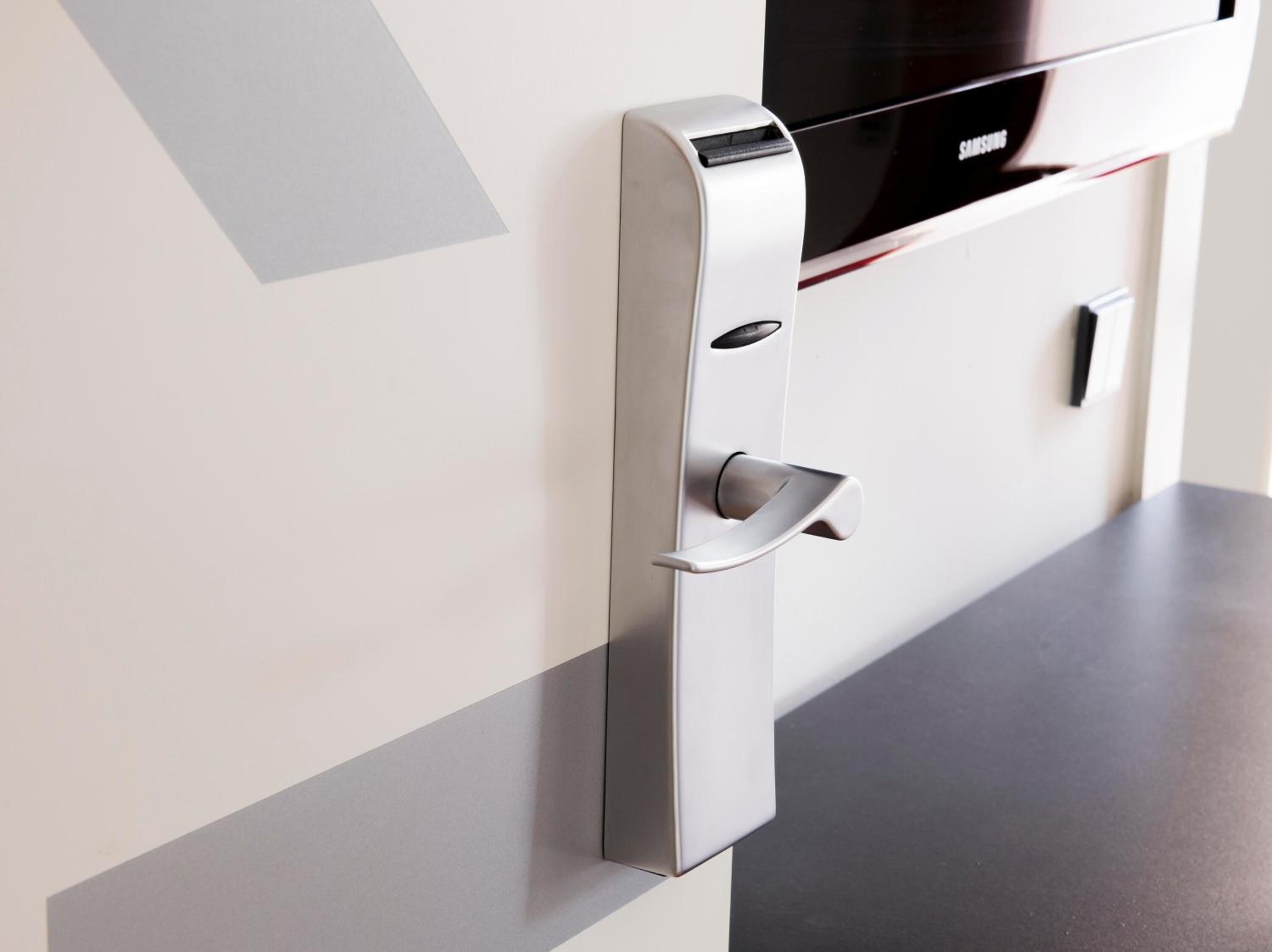 A modern, metallic door with a fingerprint scanner and a keyhole, indicating a secure entry system.