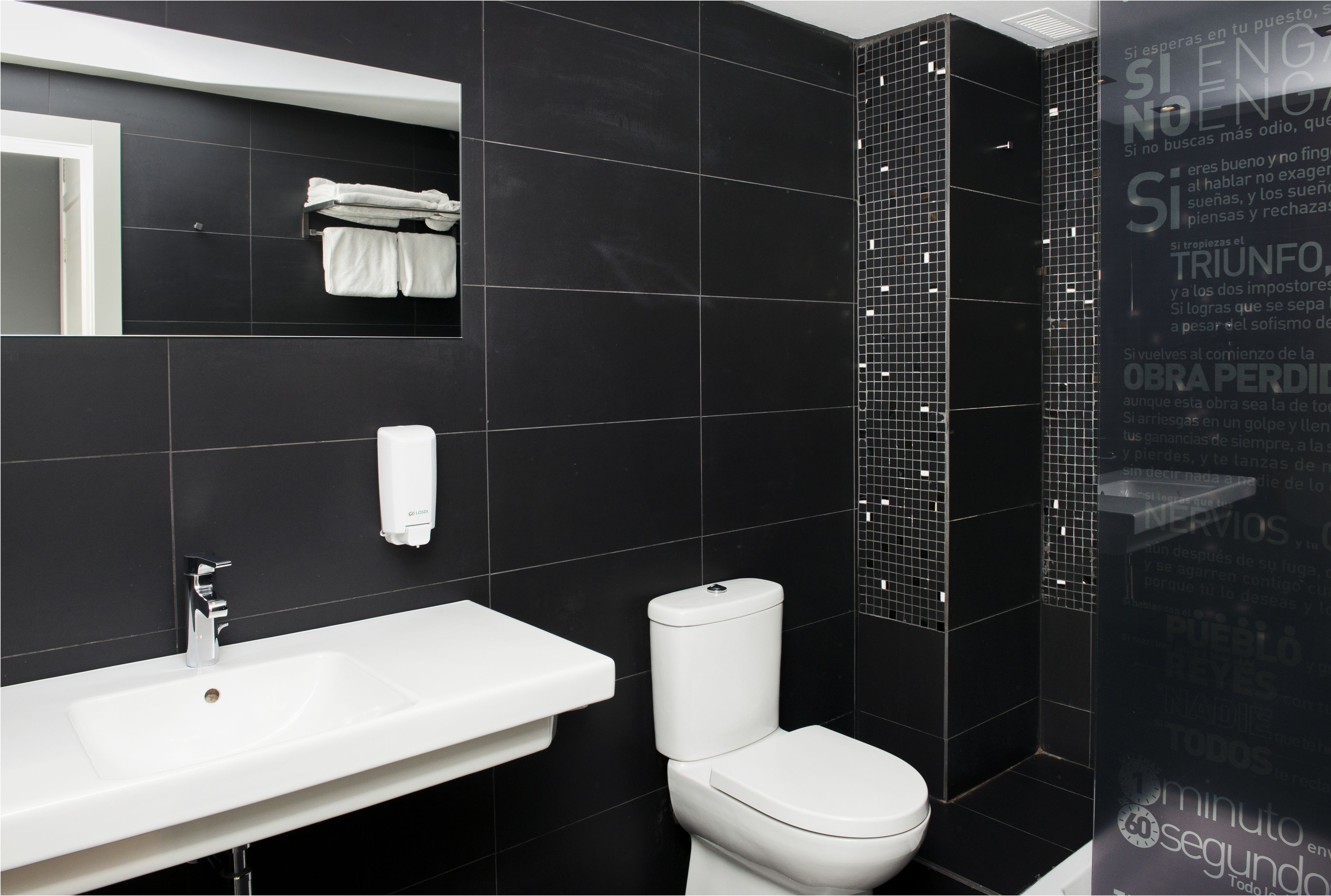 Een moderne badkamer met een wit wastafelmeubel, toilet en een handdoekhouder.