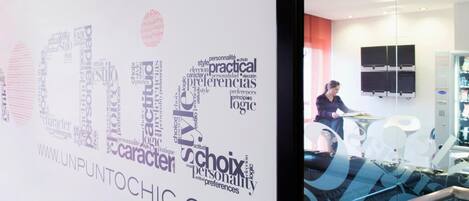 A room with a large word cloud on the wall, a flat-screen TV mounted on the wall, and a person sitting on a couch.