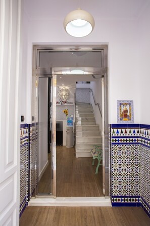 Un hall d’hôtel moderne avec un escalier, un comptoir d’accueil et des carreaux décoratifs.