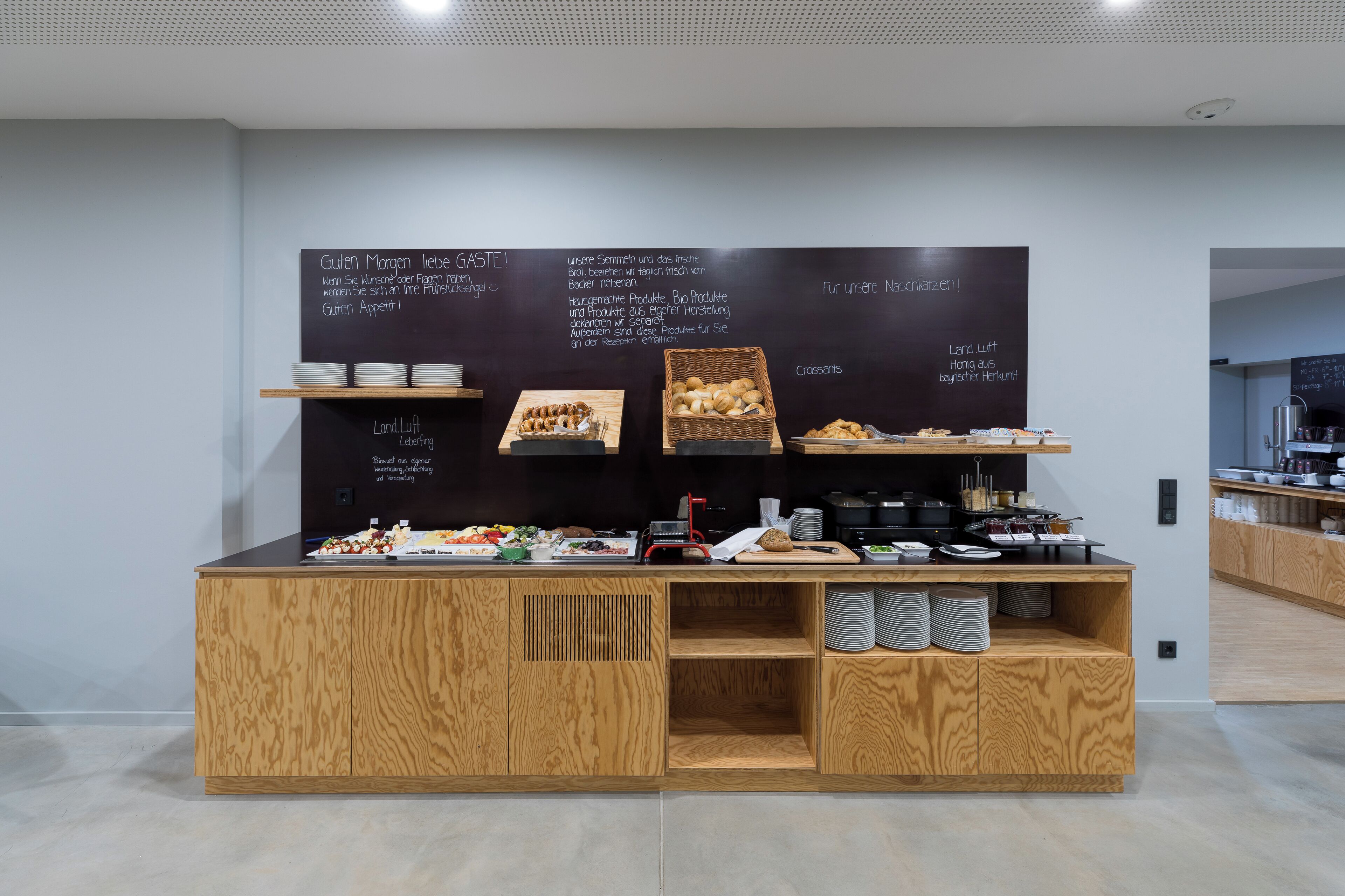 Un bar de petit-déjeuner doté de meubles en bois et d’un tableau noir où sont affichés différents plats et messages.
