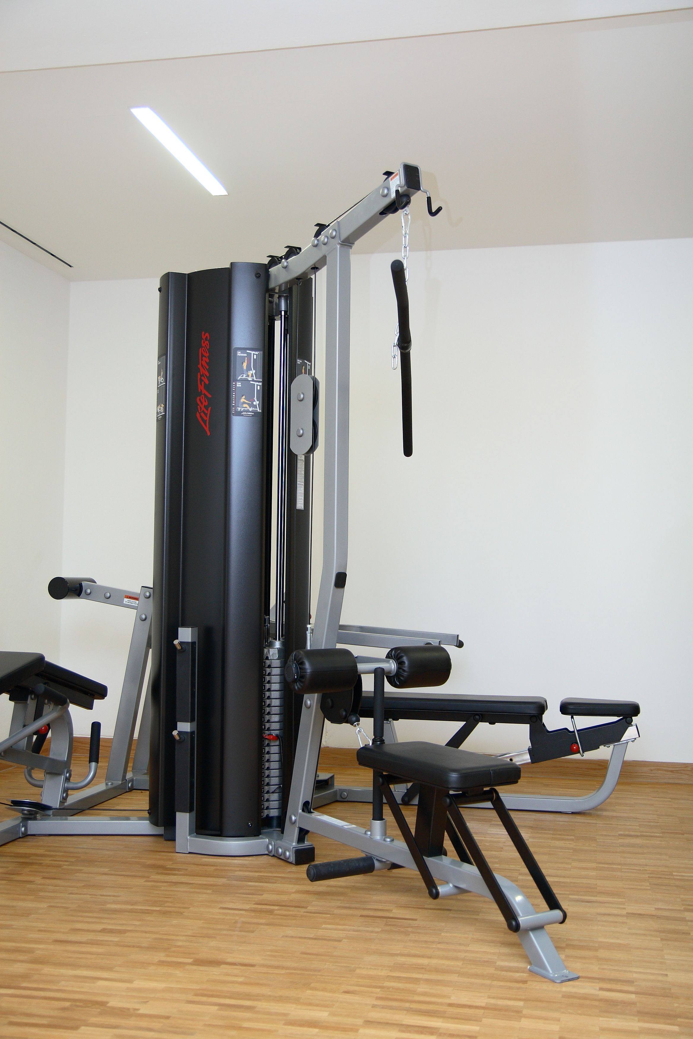 A gym with a weight machine, bench, and a pull-up bar.