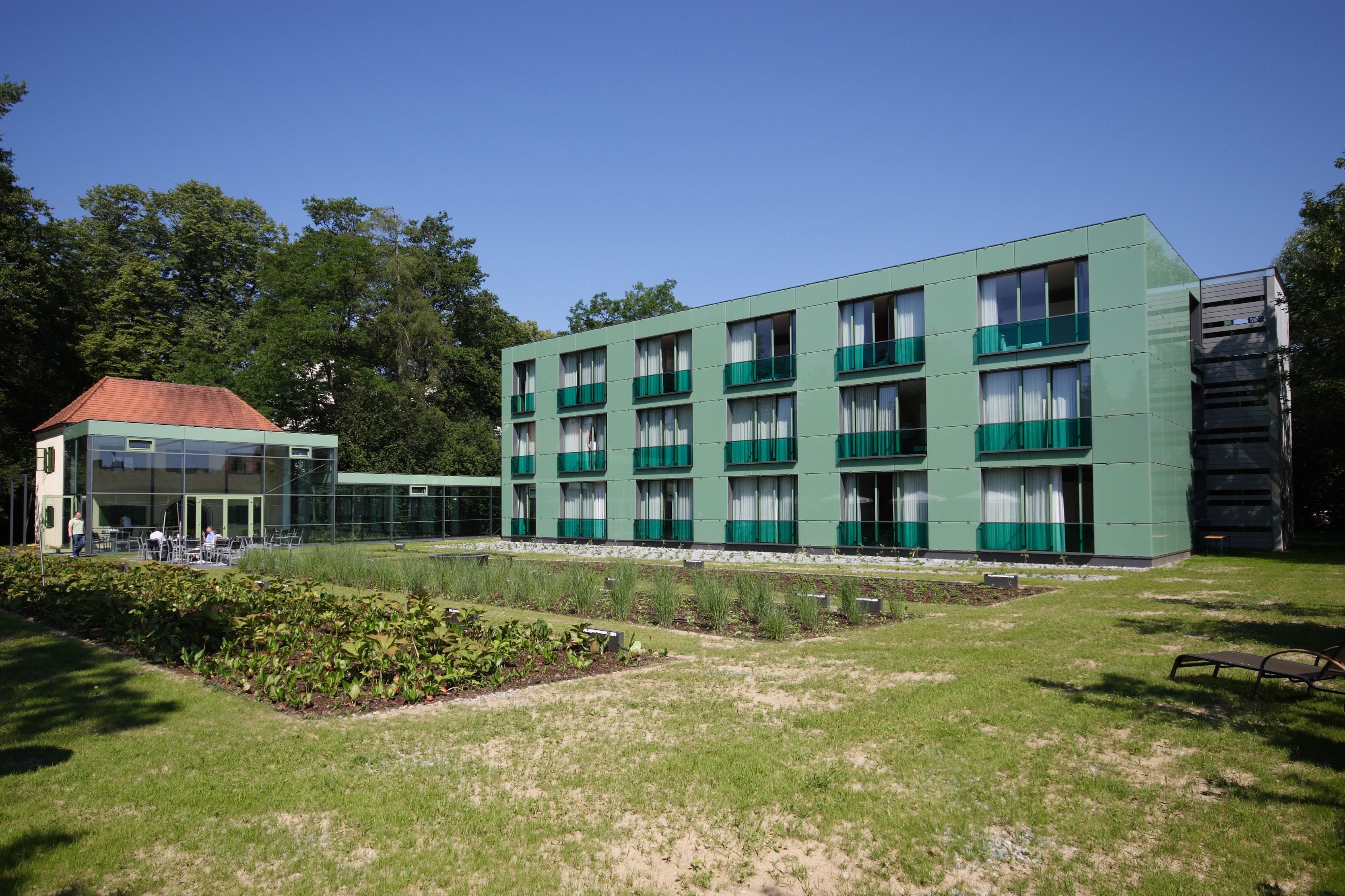 A modern building with a flat roof, multiple balconies, and a glass facade.