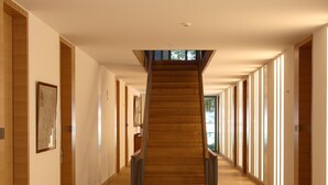 A long, narrow hallway with a wooden staircase leading to a higher floor.