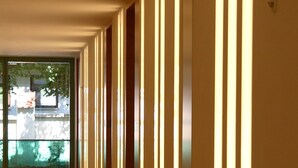 A corridor with vertical light panels and wooden flooring.