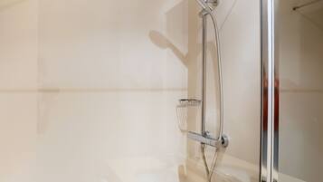 A modern bathroom with a glass-enclosed shower, a large mirror, and a beige countertop.