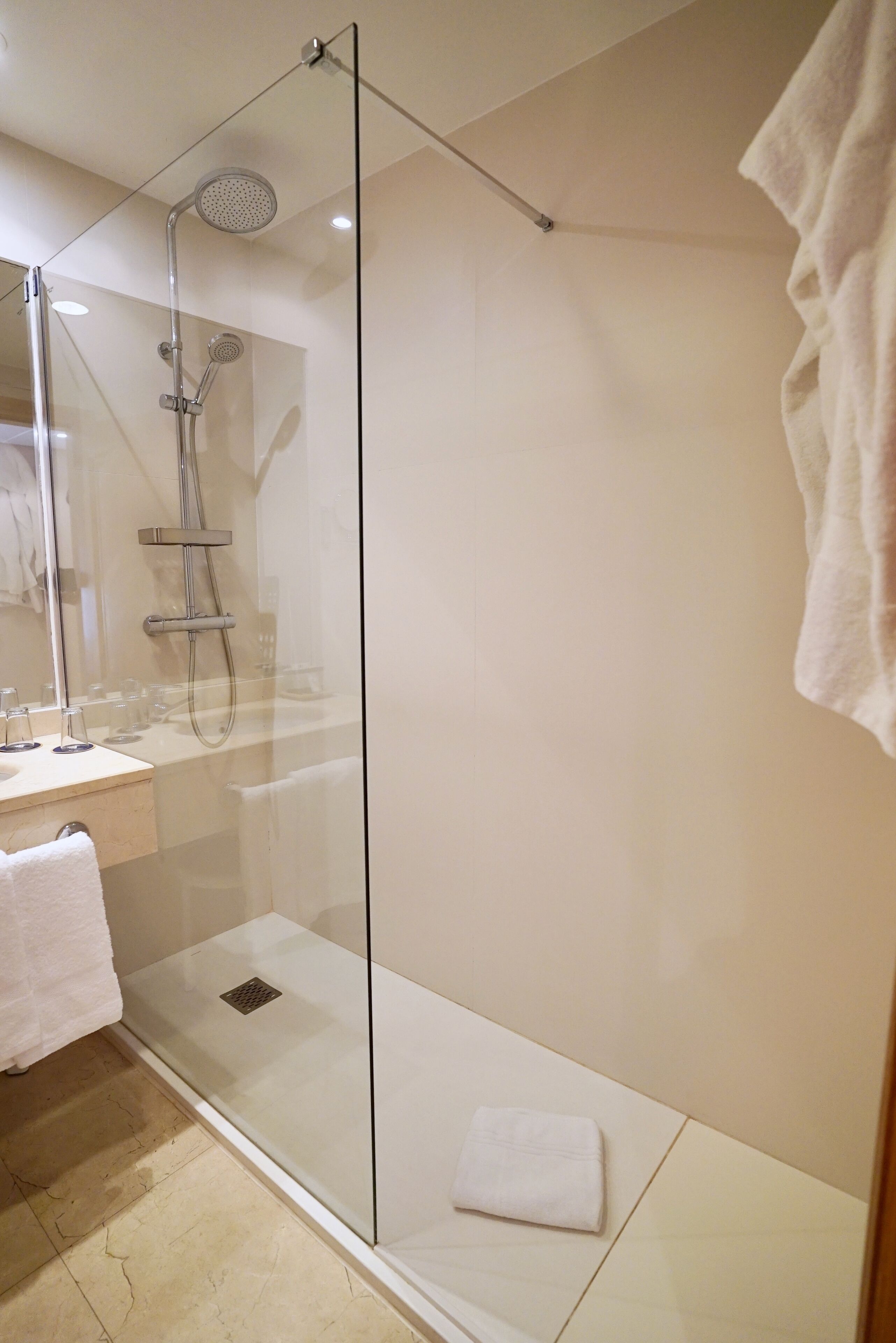 Une salle de bain moderne avec une douche à parois de verre, un lavabo blanc et un miroir.