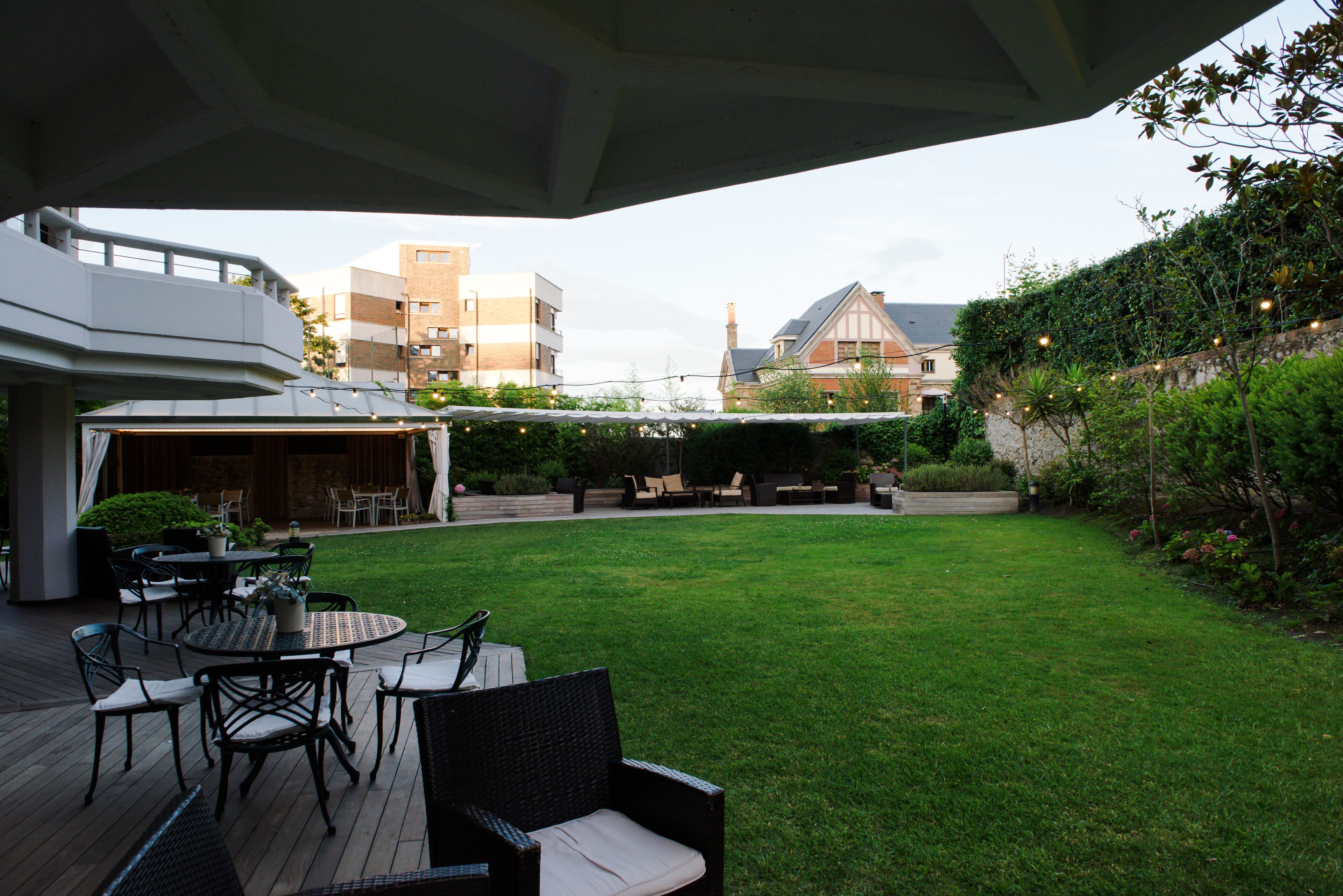 A patio area with outdoor furniture, a covered seating area, and a view of surrounding buildings.