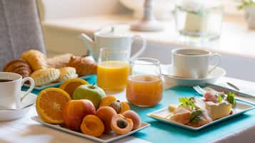A breakfast setting with croissants, fruit, coffee, and juice on a table.