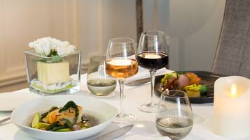 A table set with a white plate of food, two wine glasses, a candle, and a glass of water.