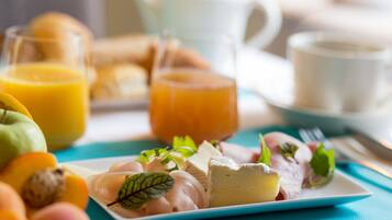Une table mise pour le petit-déjeuner, avec une assiette contenant des aliments, notamment du fromage, des fruits et une boisson.