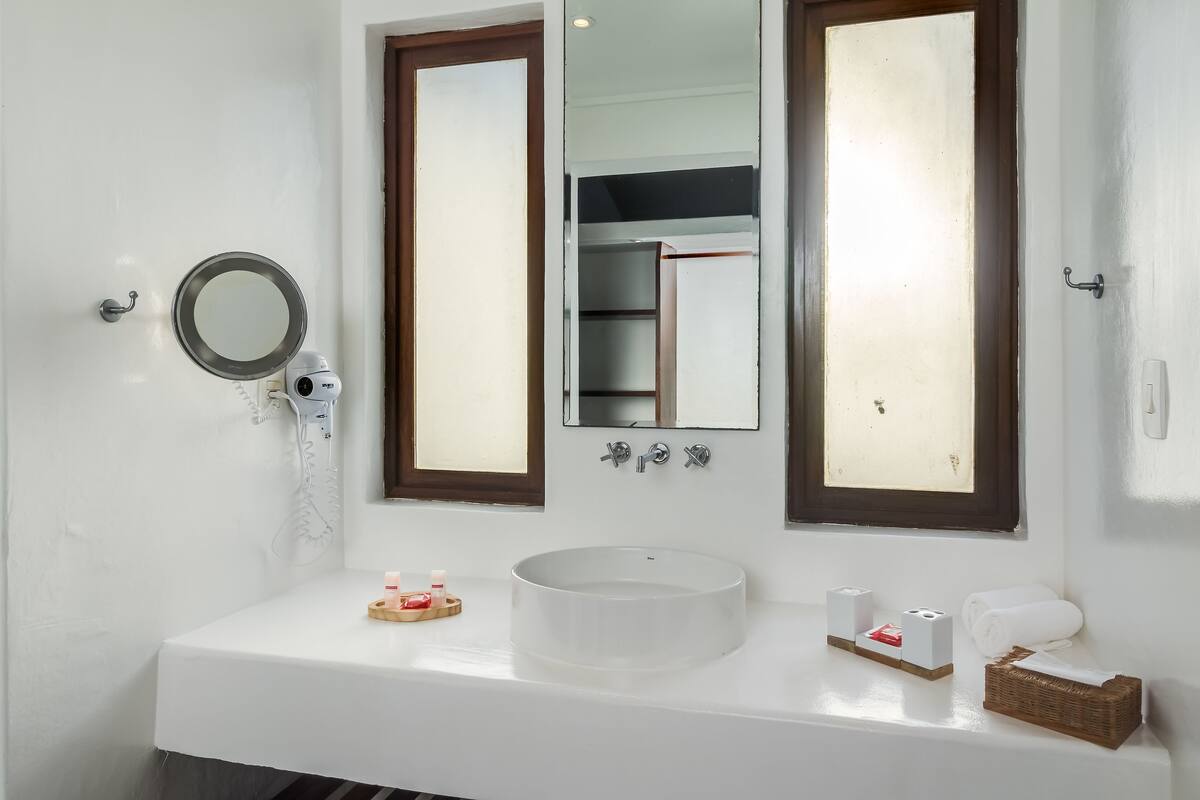 A bathroom with a white sink, a mirror, and a window.