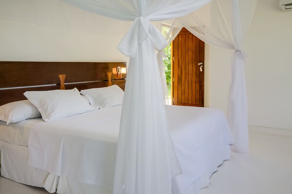 Un dormitorio con cama a dosel, cabecera de madera y vistas al exterior.
