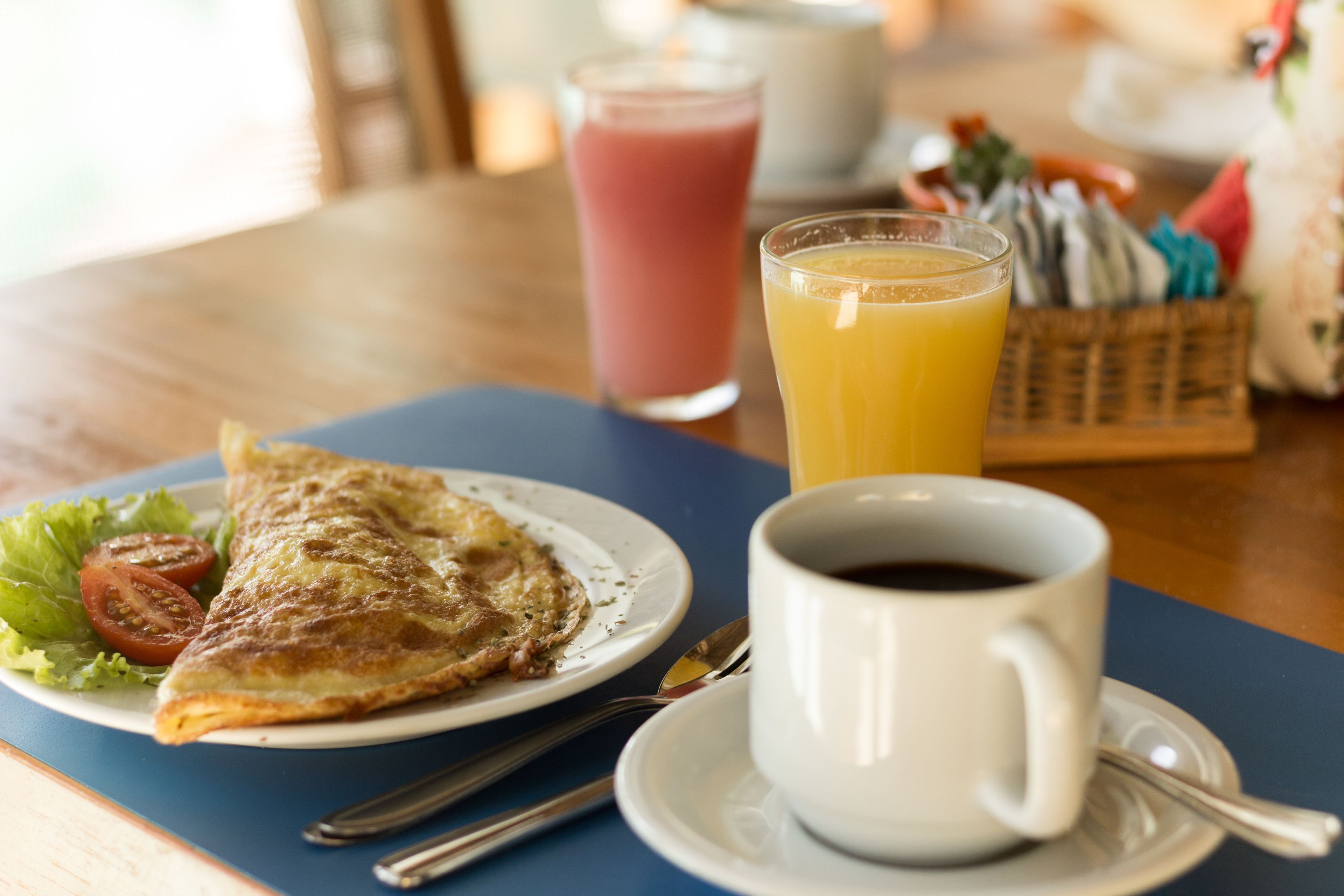 Une table mise pour le petit-déjeuner, avec une assiette de nourriture, une tasse de café et un verre de jus d’orange.