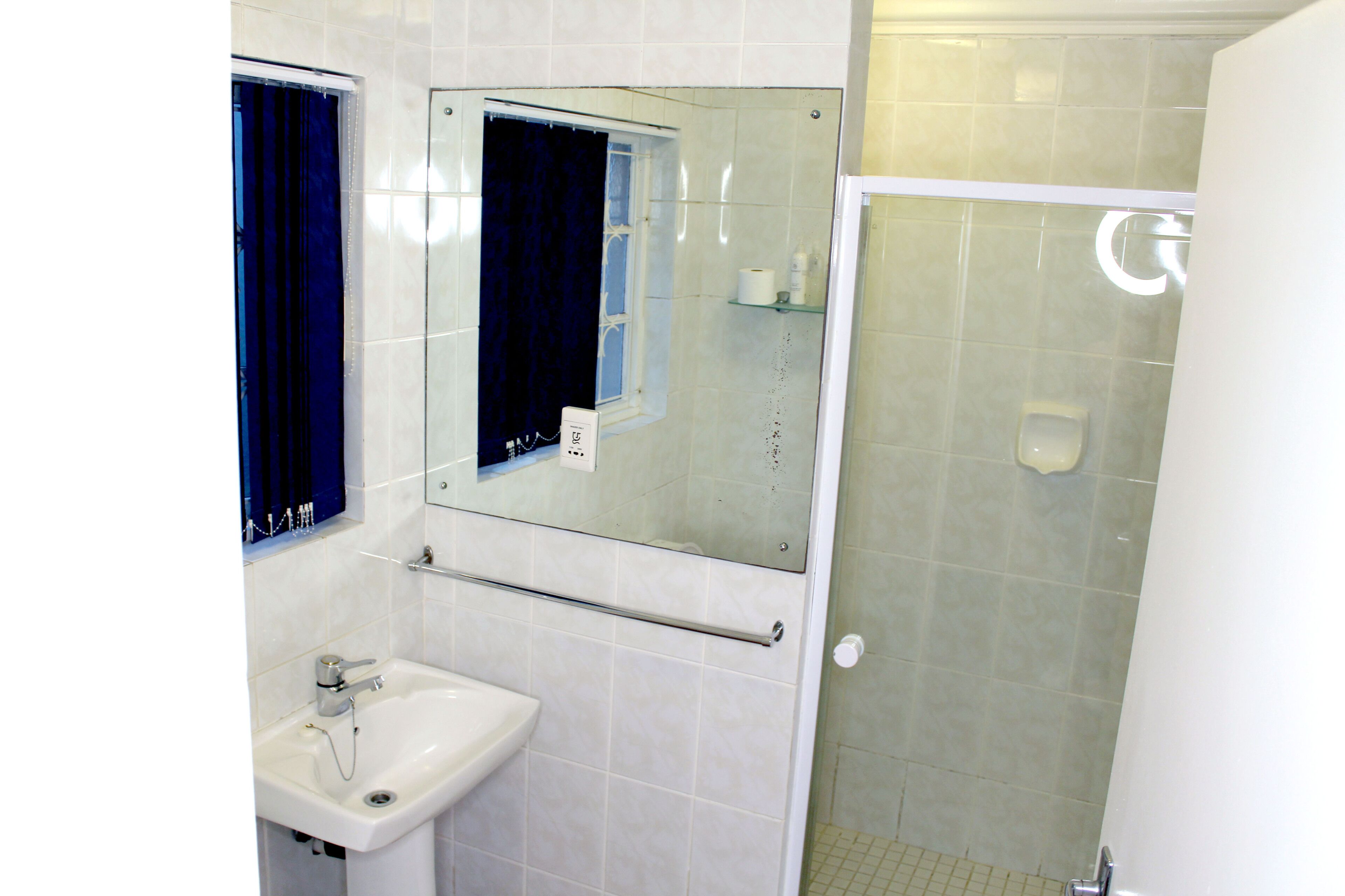 A bathroom with a sink, mirror, and shower.
