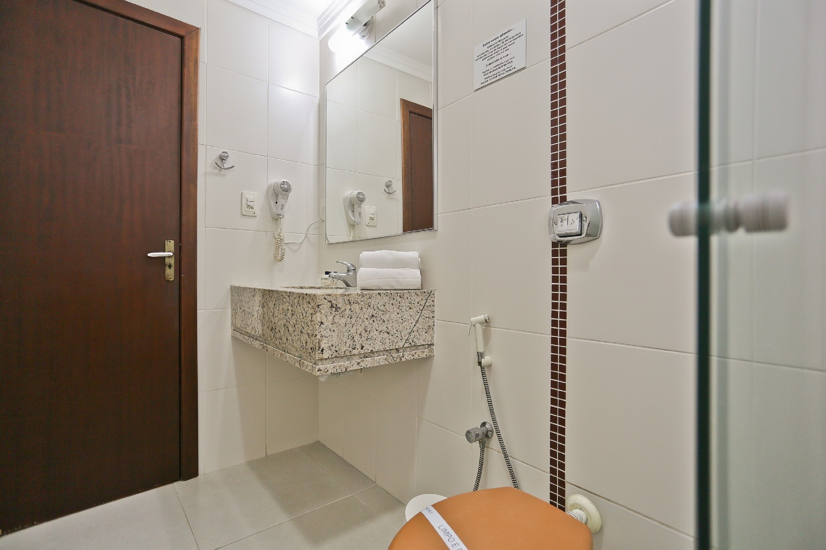 A bathroom with a marble sink, a towel rack, a mirror, and a shower area.
