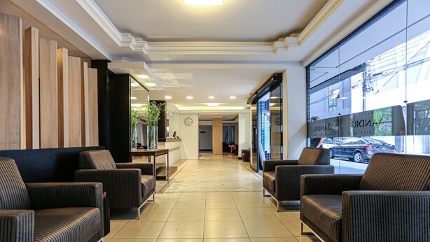 A hotel lobby with a reception desk, seating area, and large windows overlooking the street.
