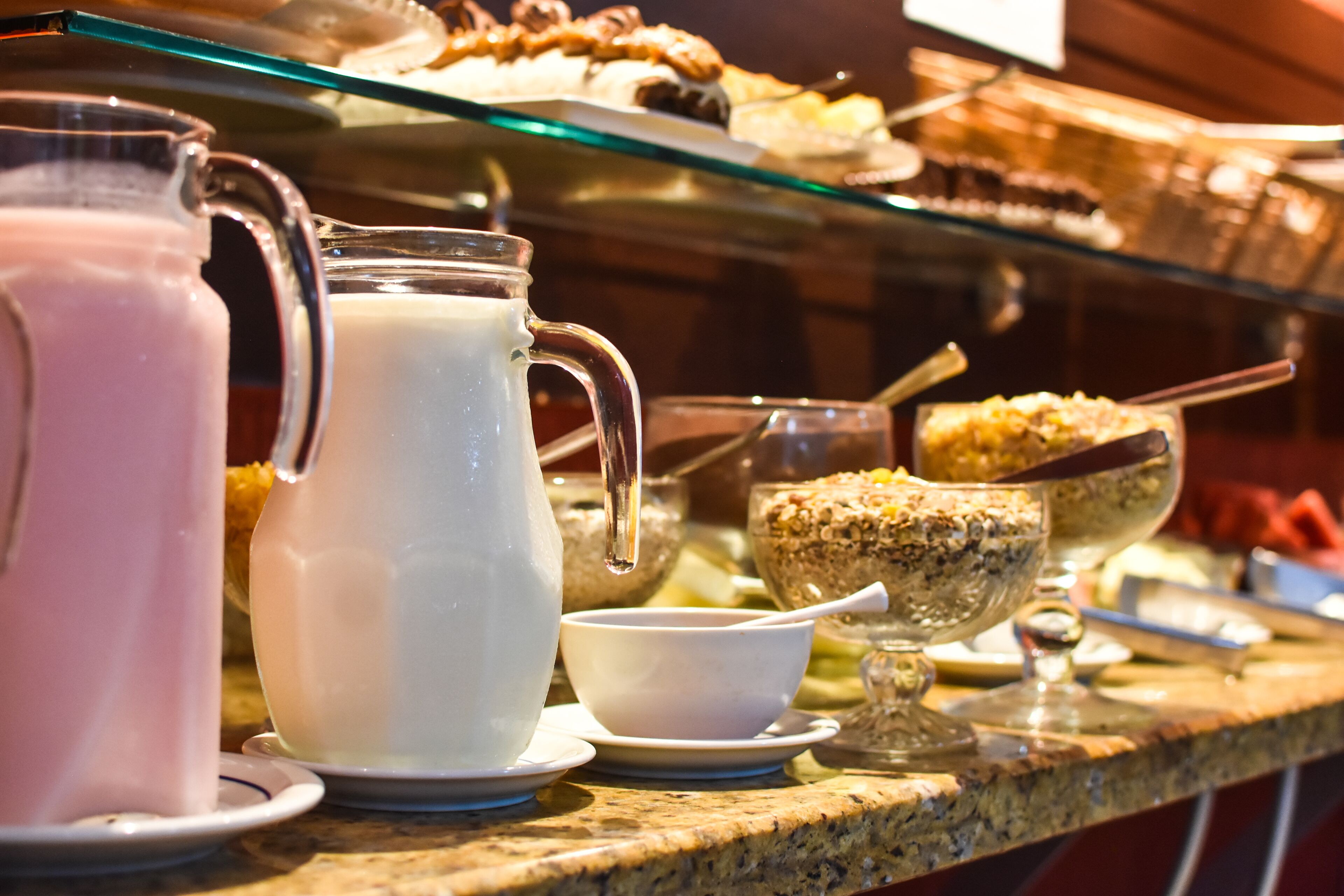 A buffet with various food items, including a pitcher of milk, a bowl of cereal, and a dessert dish.
