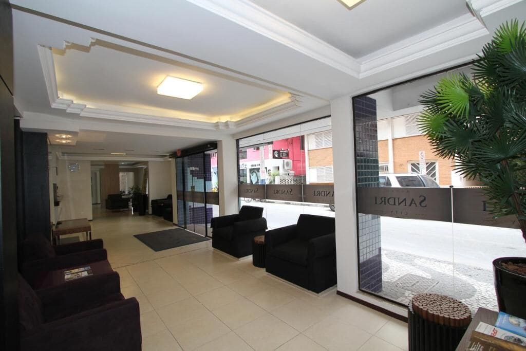 Vestíbulo de hotel con recepción, zona de estar y grandes ventanales con vistas a la calle.