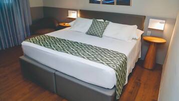 A hotel room with a large bed, two bedside tables, a headboard, and a wall-mounted artwork.