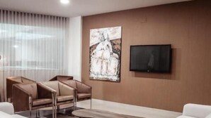 Ein modernes Wohnzimmer mit weißen Sofas, einem Couchtisch und einem an der Wand befestigten Fernseher.