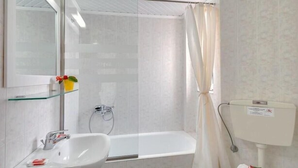 A bathroom with a white sink, a glass shower enclosure, and a toilet.