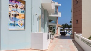 A building with a sign reading 'ATHENA APTS' and a poster advertising a swimming pool and snack bar.