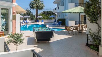 A pool area with lounge chairs and a foosball table.