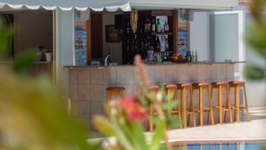 A poolside bar with stools and a signboard listing food and drink options. - Athena Apartments (Hersonissos)