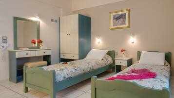 A bedroom with two single beds, a wardrobe, a desk, and a mirror.