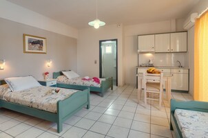 Una habitación con dos camas, una pequeña cocina y un comedor.