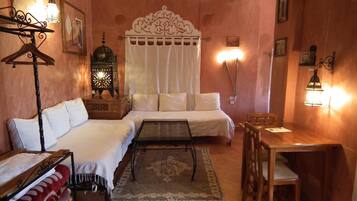 Habitación de hotel con cama, sofá, mesa, silla, lámpara colgante, aire acondicionado instalado en la pared y un farol decorativo.